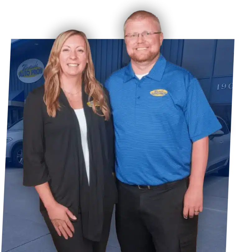 Auto Repair in Clive, IA At Westside Auto Pros. A woman in a black outfit and a man in a blue polo shirt stand smiling together in front of a building with a Westside Auto Pros sign.