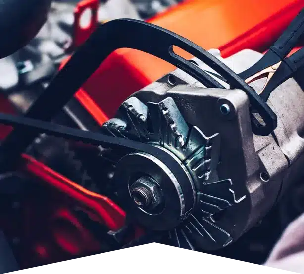 Alternator Repair & Services in Clive, IA At Westside Auto Pros. Close-up of a car engine component, showing a metal alternator with a black belt and red engine parts in the background.