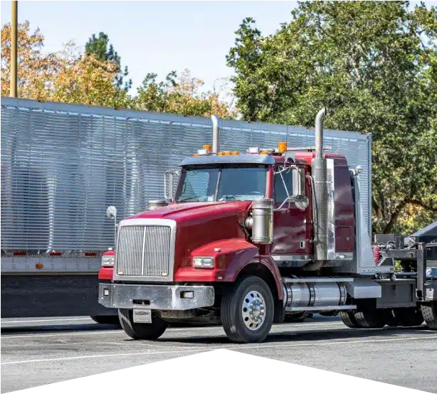 Fleet Maintenance Services in Clive, IA At Westside Auto Pros. A red semi-truck parked next to a large silver trailer on a sunny day, with trees and greenery in the background.