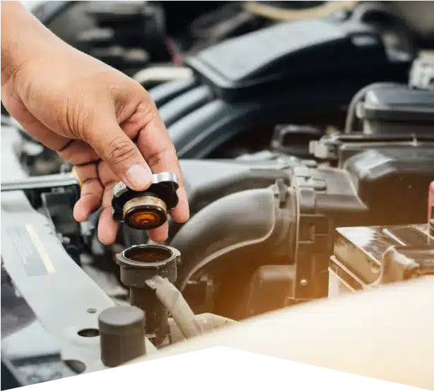 Radiator Repair in Clive, IA At Westside Auto Pros. A person’s hand removes a radiator cap from a car engine, with the engine components visible in the background.