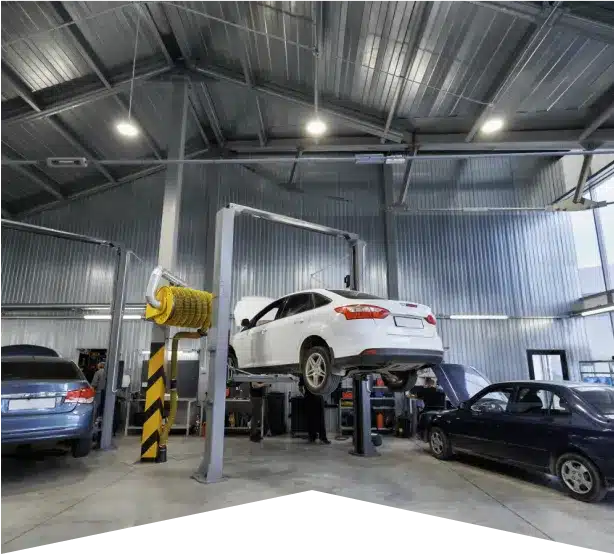 Auto Repair Services in Clive, IA At Westside Auto Pros. A white car is elevated on a hydraulic lift inside a spacious, modern auto repair shop with metal walls, bright lighting, and other parked vehicles nearby.