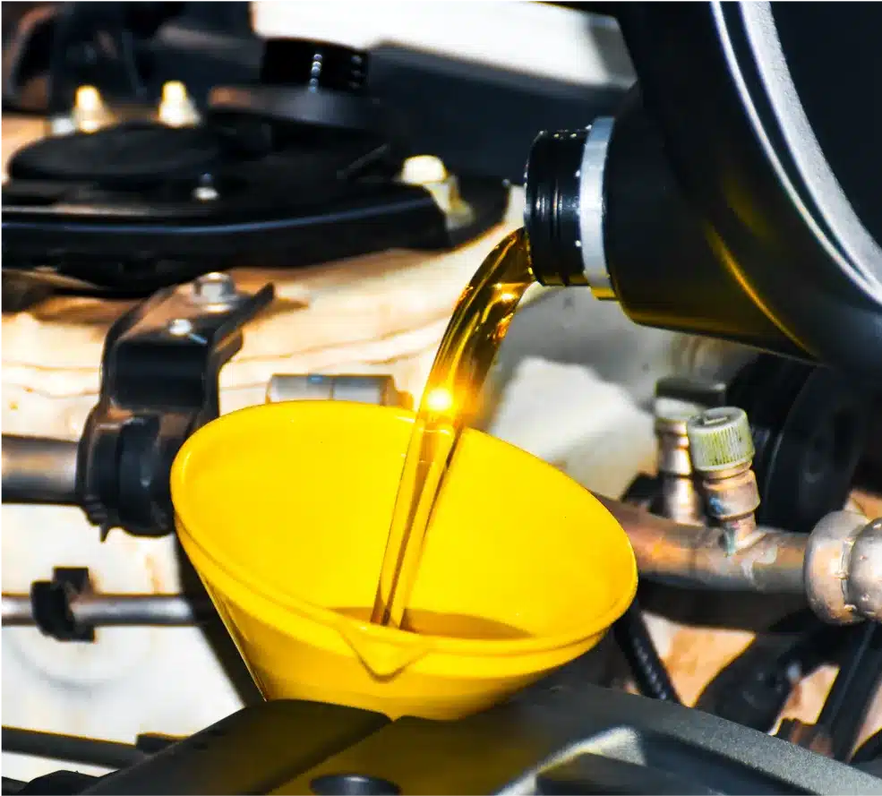 Preventative Maintenance & Oil Change in Clive, IA At Westside Auto Pros. Close-up of motor oil being poured from a black container into a yellow funnel placed in a car engine during an oil change.