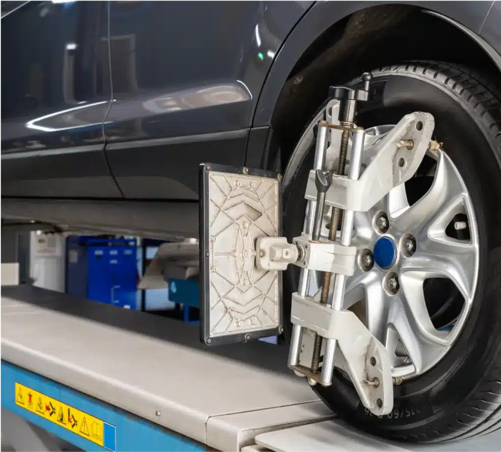 Wheel Alignment in Clive, IA At Westside Auto Pros. A car wheel is being aligned using a specialized alignment tool mounted on the rim, with the vehicle positioned on a platform in an auto repair shop.