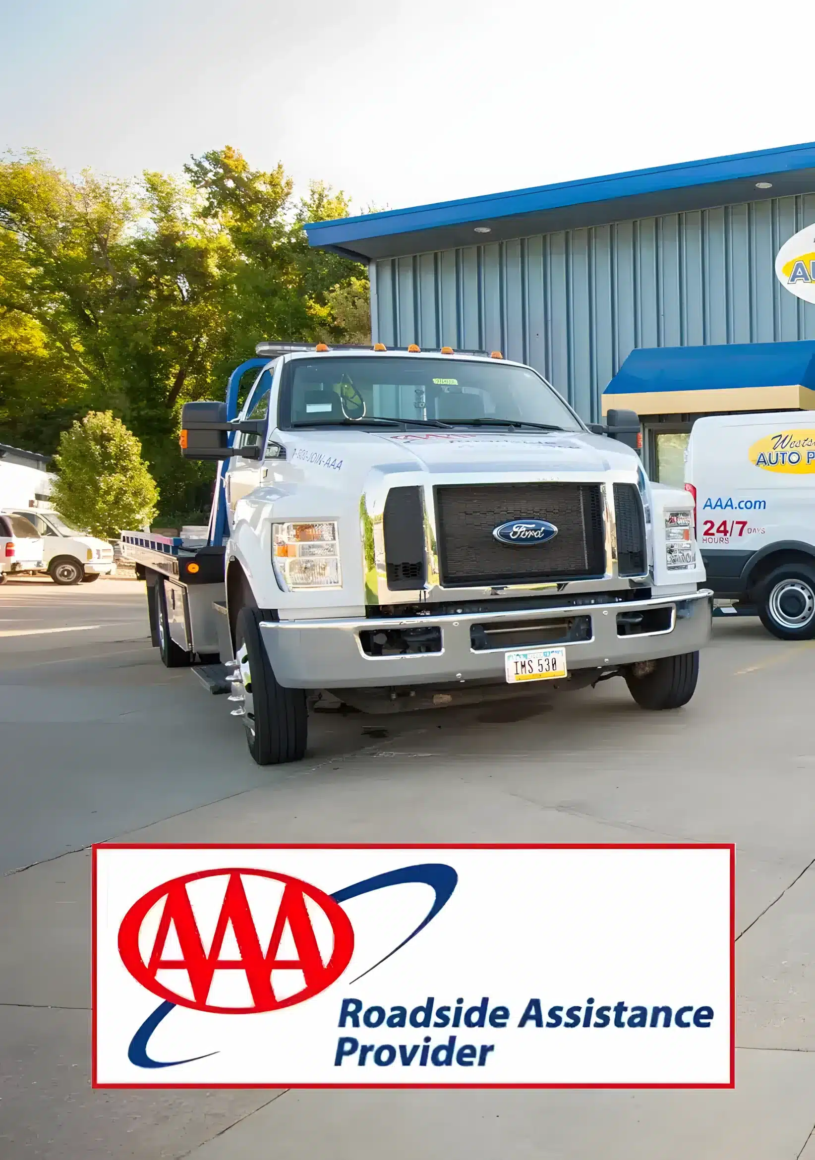 A white AAA tow truck, part of their trusted towing service, is parked in front of an auto facility. The AAA logo and Roadside Assistance Provider text appear at the bottom, with another AAA van visible in the background.