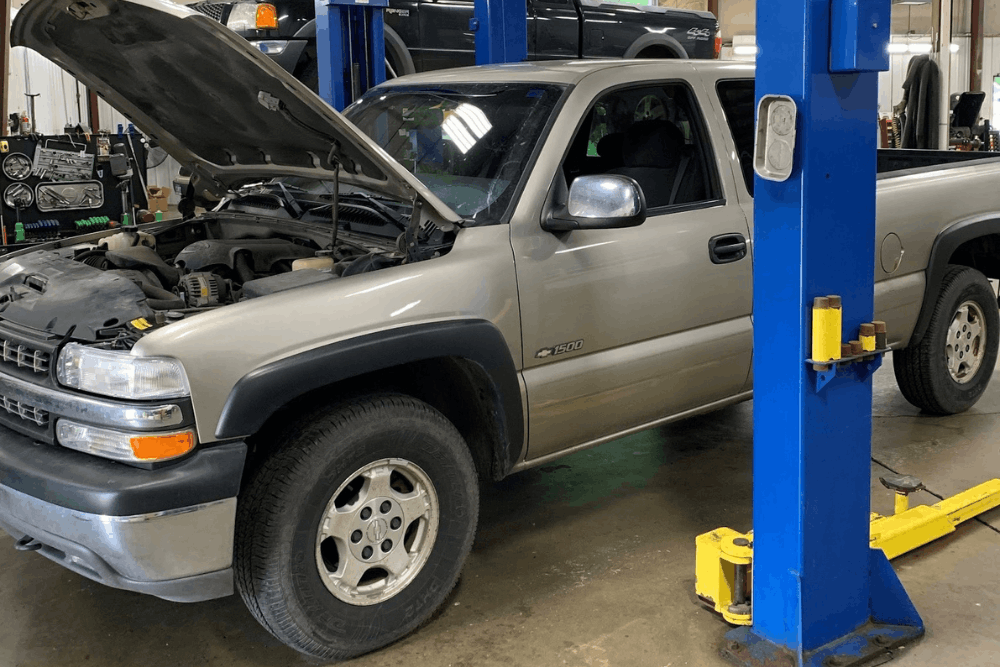 Diesel repair in Clive, IA at Westside Auto Pros. Image of two pickup trucks inside an auto repair shop with their hoods open near service lifts for inspection and maintenance.